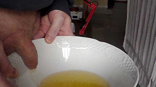 John is pissing in a bowl in closeup